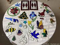 Overview of all stained glass pieces laid out on a round table, showing variety in colors and motifs