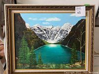 Frontal photo of original oil painting showing lake, mountains, trees, and gold frame.