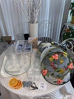 Photo showing overall lot with clear plastic trays, champagne flutes, tall glasses, floral mesh covers, vase with faux branches, napkin holder, orange coasters, and metal accessories.