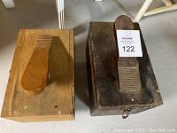 Two wooden shoe shine kits with shoe-shaped pedals on top, placed side by side
