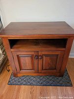 Front view of wood cabinet showing open shelf and double-door cupboards below