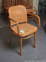Front and partial side view of bentwood armchair with cane seat and backrest showing overall shape and condition.