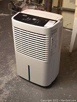 Front angle view of the dehumidifier showing vent grill, water level indicator slot and body condition.