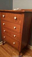 Full view of solid wood dresser with four drawers and new white round pulls.