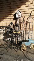 Overall view of lot showing plant stands, obelisks, lanterns, birdhouse, decorative cart