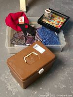 Overview of lot showing scarves inside plastic bin, brown notions box in front, shadowbox with buttons on top