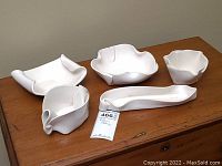 Overview of five white Hillborn ceramic bowls and dishes on wooden surface