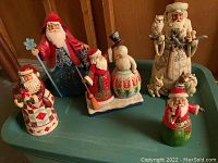 Five Jim Shore Santas arranged on tote lid.