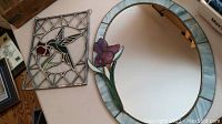 Photo showing the oval mirror with flower decoration next to the hummingbird stained glass panel.