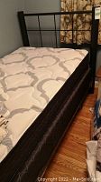 Full view of assembled bed showing headboard, mattress, boxspring and frame on casters