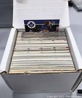Photo showing one box open with a stack of assorted Toronto Maple Leafs hockey cards inside, featuring varied card designs and a 'Pro Set' card visible on top.