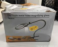 Damaged box of clip-style metal hose magnifying glass showing product image and details including JM509-A model and LED lights.