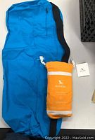 Blue Bean brand carrying case with black and blue handles next to orange Dock & Bay towel pouch