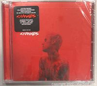 Front cover of Justin Bieber Changes album CD showing red background with side profile portrait and sticker.