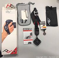 Overview of all included items showing strap, packaging, pouches, hardware, and manuals arranged on flat surface
