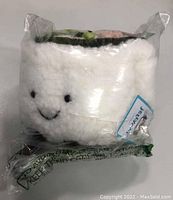 Front view of the Sushi Plush Doll still sealed in clear plastic packaging showing the smiling face and sushi detail.