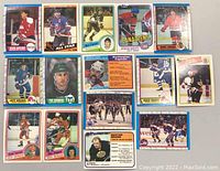 Image shows an assortment of 16 vintage hockey cards from the 1980s laid flat on a surface. Cards depict players from various NHL teams including Washington Capitals, Hartford Whalers, Detroit Red Wings, Montreal Canadiens, and Boston Bruins.