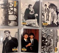 Six collectible Beatles cards in plastic sleeves, arranged in two rows of three. Each card features black and white images of The Beatles band members in various poses and performance settings, all marked with The Beatles Collection logo in color.