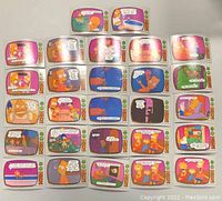 Overview photo showing all 27 colorful Simpsons trading cards laid out in rows with various character scenes and dialogues