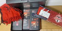 Two red Toronto FC scarves in original boxes with season ticket booklet visible inside one box.