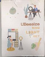 Damaged packaging box front with colorful illustrations of people using UBeeSize ring light for makeup and video recording.