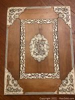 Overall view of the rectangular carved box top showing decorative corners and central inlaid medallion.