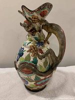 View of antique ceramic dragon vase front showing dragon head and floral painted body