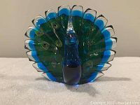 Front view of the Dynasty Galleries art glass peacock, showing detailed glass tail feathers and body.