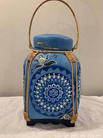 Front view of medium blue boho wicker decorated lidded basket with mandala patterns and handle