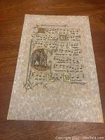 Full view of the sheet music showing decorated staff lines and gold leaf embellishments around the text and designs.