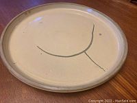 Top view of the pottery platter showing the modernist black linear design on beige glaze surface.