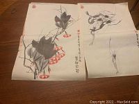 Two Chinese ink paintings on paper shown side by side on a wooden surface, visible calligraphy and red seals present.