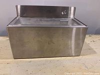 Front angle view of vintage stainless steel wall mount ashtray on a surface