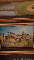 Close-up of small oil painting showing barn, field, and church steeple in a gold colored frame.