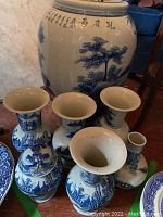 Overall view: one large lidded jar behind six small flared-neck vases