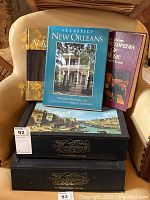 Photo showing six hardcover books arranged on a chair, including Classic New Orleans, Encyclopedia of Music, Vatican book, and four volumes of The World Greatest Paintings.