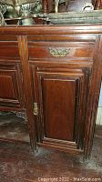 Front left view showing paneled drawer, door, fluted column leg and brass pull.