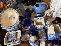 Overview of blue and white china collection including teapot, canisters, bottles, bowls, and plates on a table