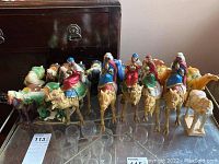 Wide shot of all seven Wise Men and camels arranged in a row on a table