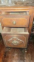Close-up of drawer details showing carved wooden panels and brass knobs.