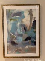 Framed abstract artwork showing layered blues, silver, and pastels with white linear accents, inside wood-tone frame with white mat.