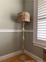 Full view of the antique beige floor lamp showing the lamp base and wicker shade in a corner.