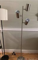 Silver floor lamp with three cylindrical adjustable heads, round base
