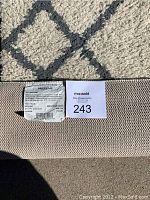 Close-up photo of the rug's surface pattern and textured rubber backing including the Project 62 label and MaxSold auction tag.