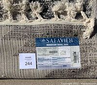 Close-up of rug label and fringe showing Safavieh Moroccan Tassel Shag label with size and material information