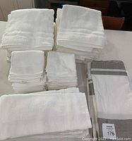 White towels in various sizes (bath, hand, face) stacked with folded gray and white shower curtain and liner.