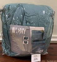 Photo of the packaged 7-piece VCNY Home queen comforter set in teal with branding showing on package label including 'Caroline Comforter'