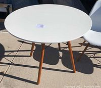 Round white table with wood legs and one chair