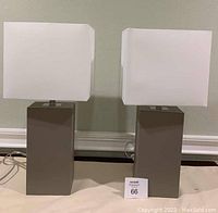 Both gray leather table lamps with white square shades side by side on floor.
