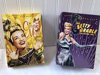 Two DVD box sets side by side, The Carmen Miranda Collection on the left in yellow, and The Betty Grable Collection Vol. 1 on the right in purple.